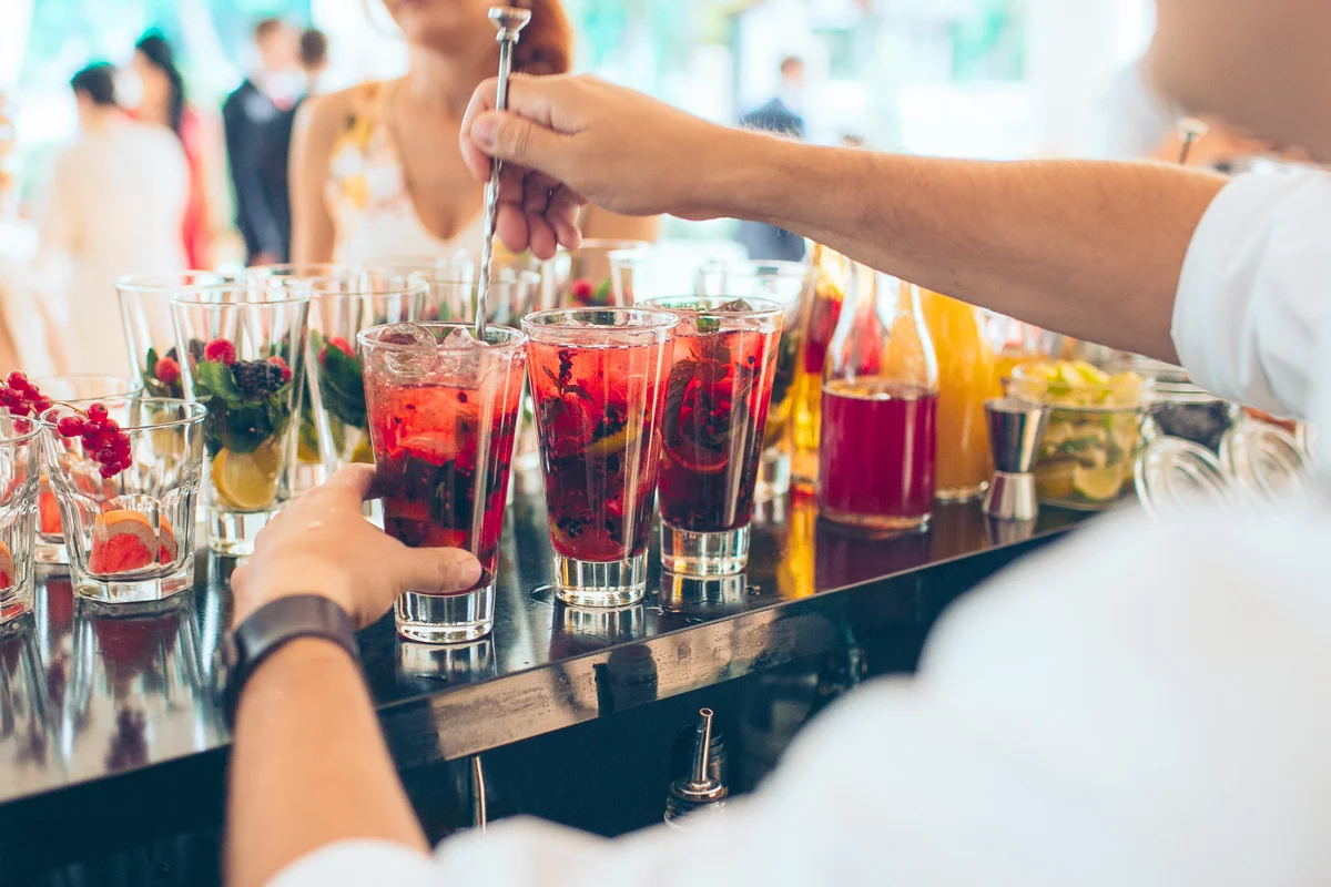 Bartender making red cocktail at the open-air wedding party