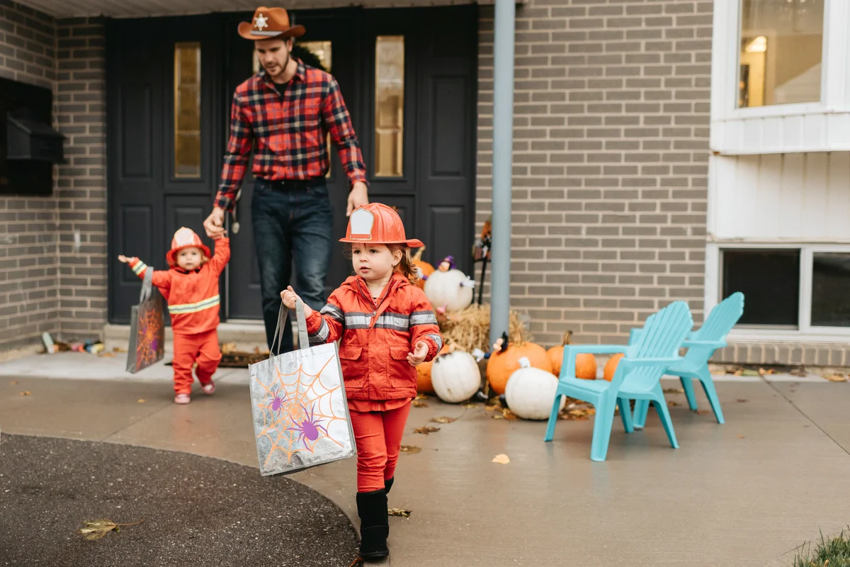 Two children dressed as firefighters caring trick or treat diy bags
