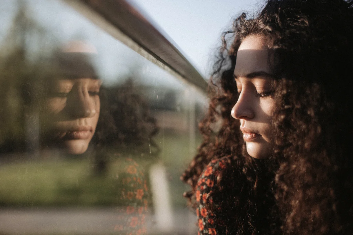 Sad young Woman Looking Through Window