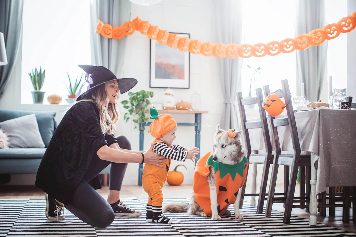 Mother helping baby to walk on Halloween