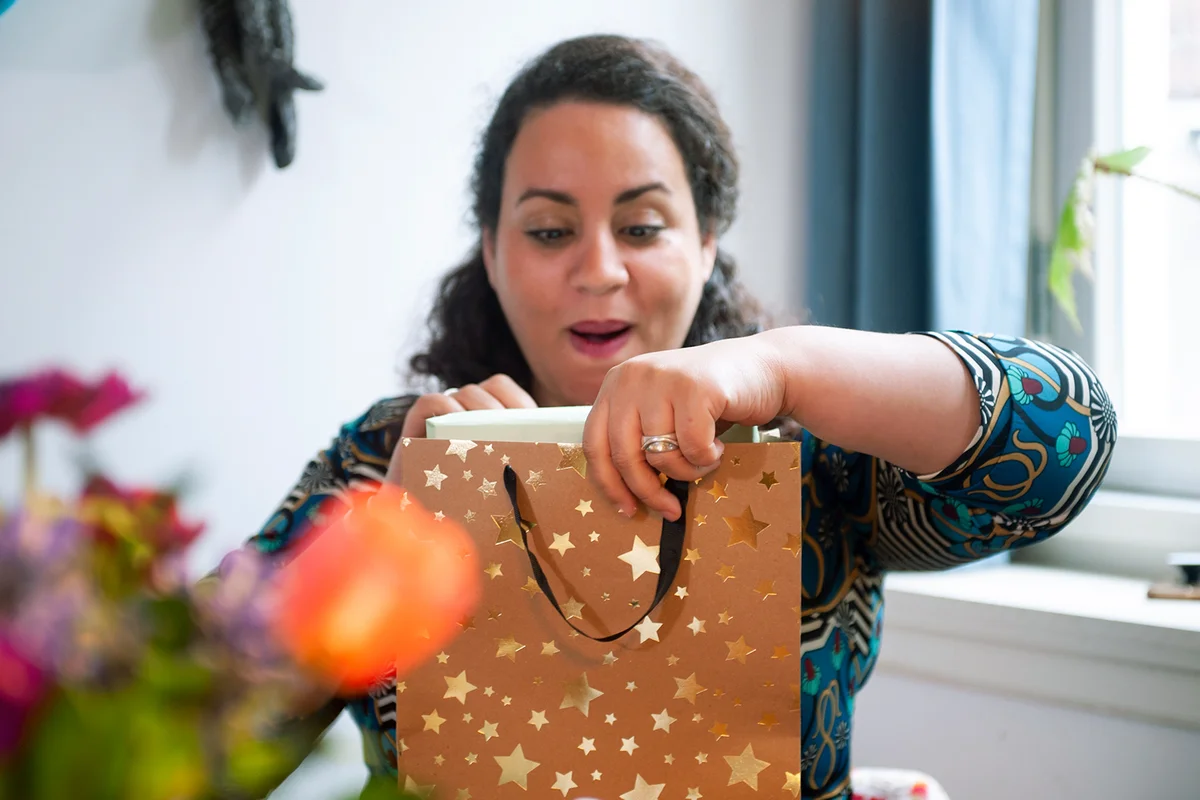 Birthday woman is opening a gift bag with her present