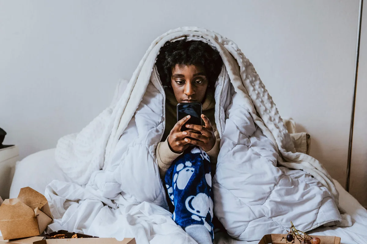 Young woman using smart phone while sitting in bedroom