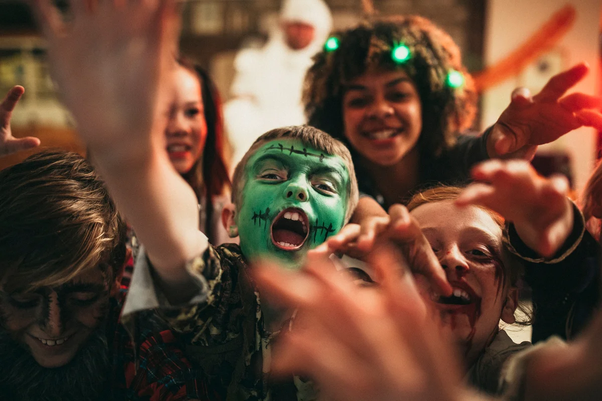 Group of young friends dressed in costumes reaching out towards the camera like zombies.