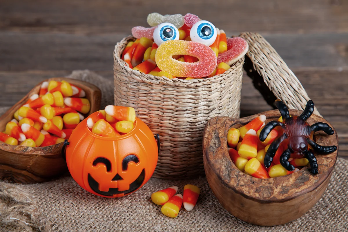 Bowls of Halloween Candy Corns and Jack O' Lantern on Wooden Rustic Table