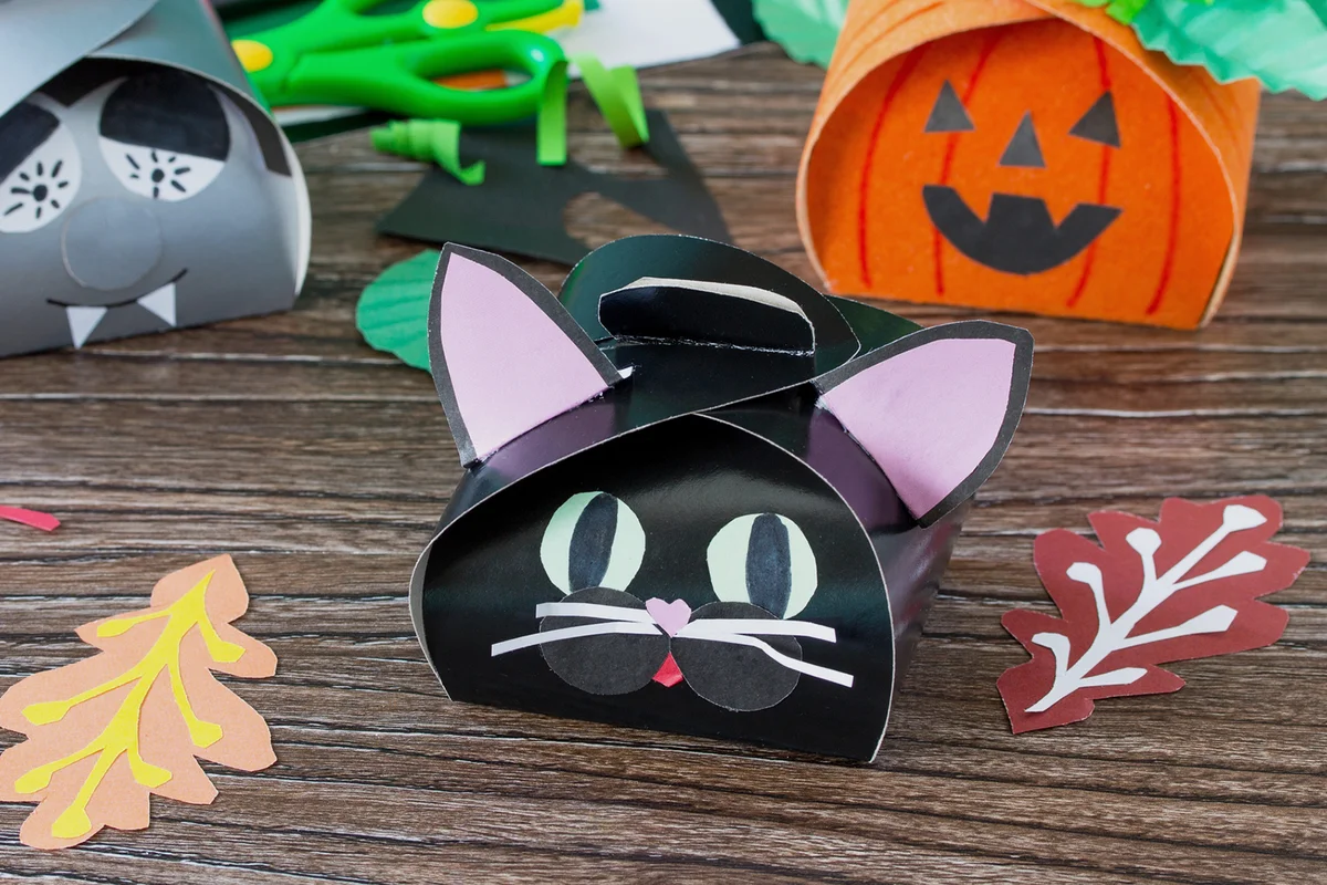 The child creates a gift box of the black cat of Halloween