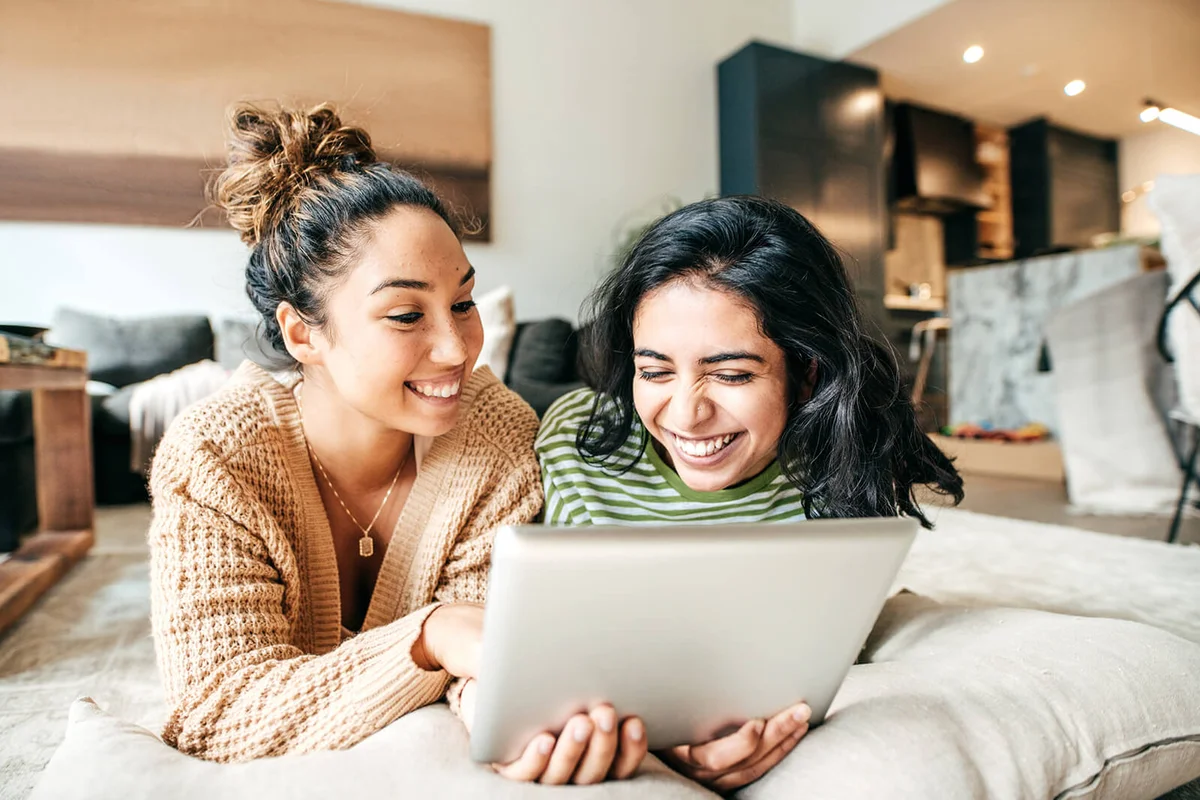 Two female students with digital tablet and cellphone at home