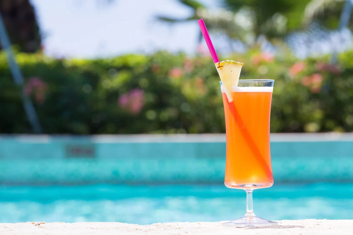 Glass of Mai Tai cocktail on the pool nosing at the tropical resort