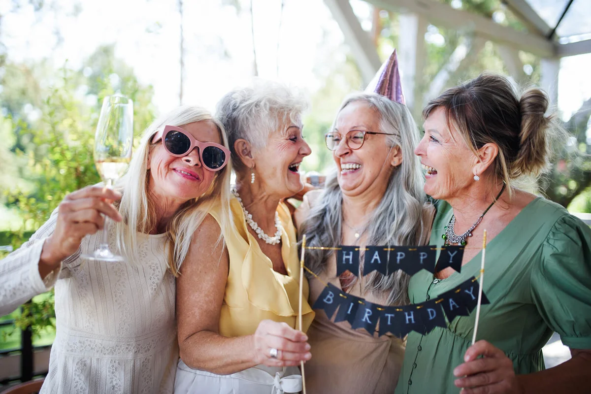 Senior women holding birthday cake during celebration outdoors on patio at restaurant