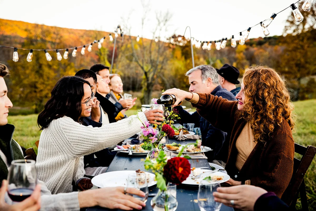 Woman pouring a glass of wine for guest at dinner party