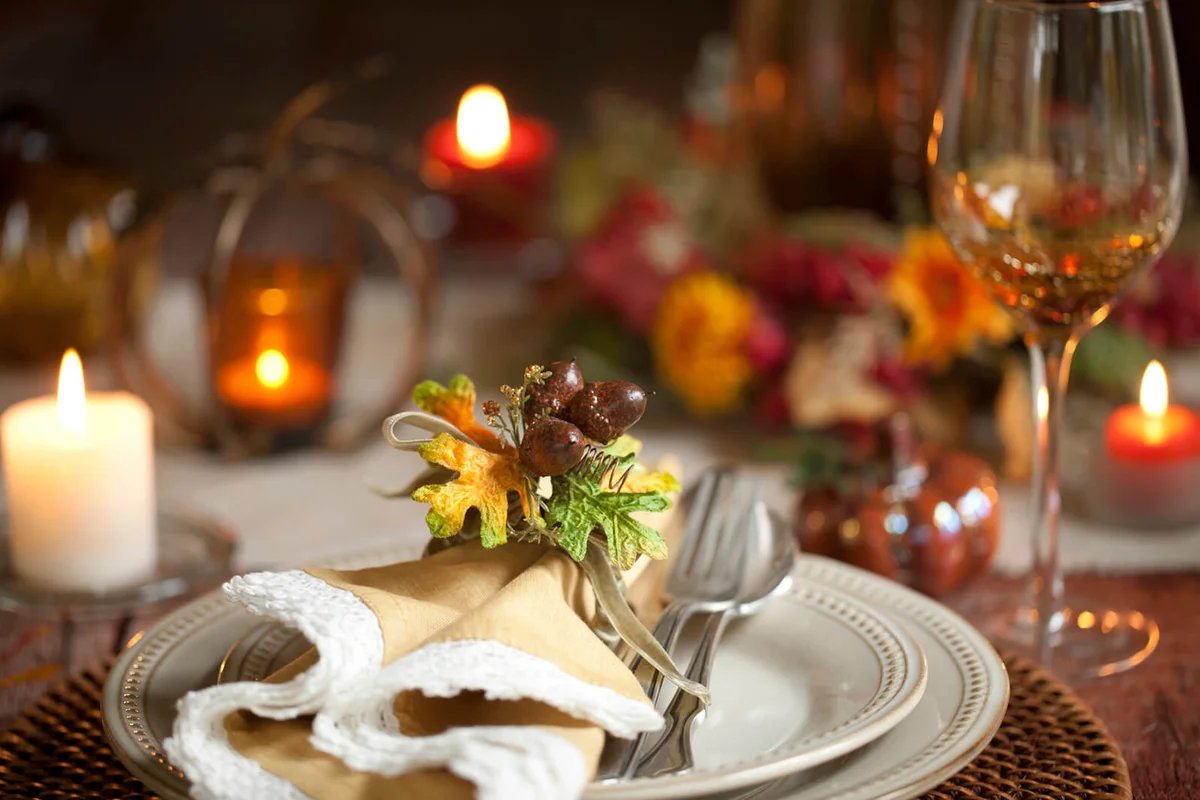 Elegant autumn Thanksgiving dining place setting on an old rustic wood table with candles