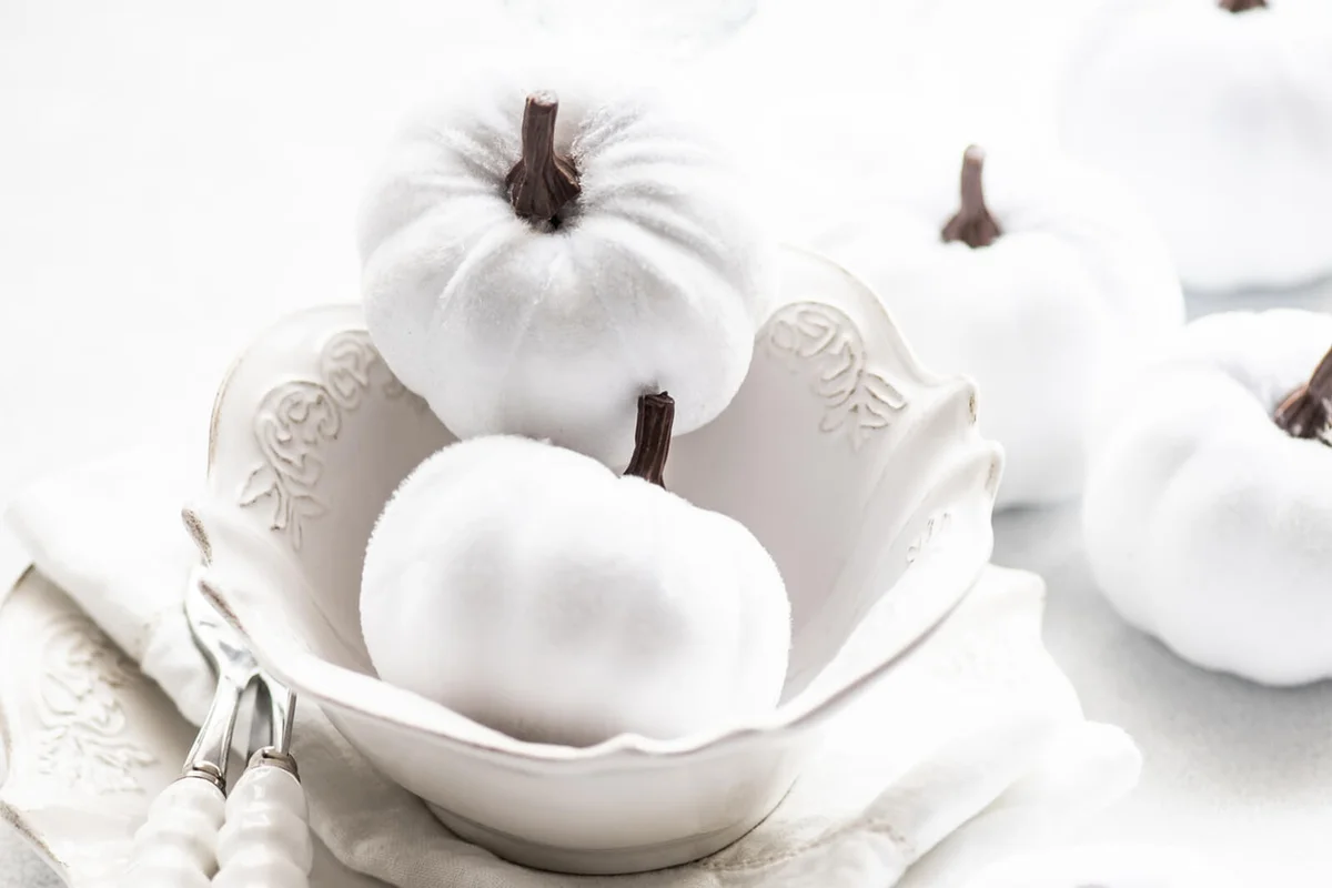 Autumnal Thanksgiving place setting on a table with pumpkin ornaments