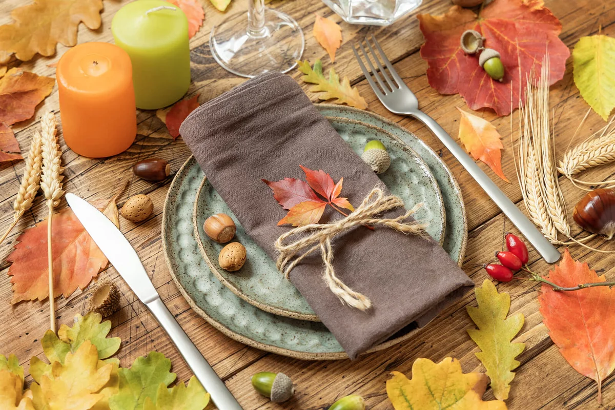 Autumn rustic table setting between leaves and berries on vintage wooden table close up