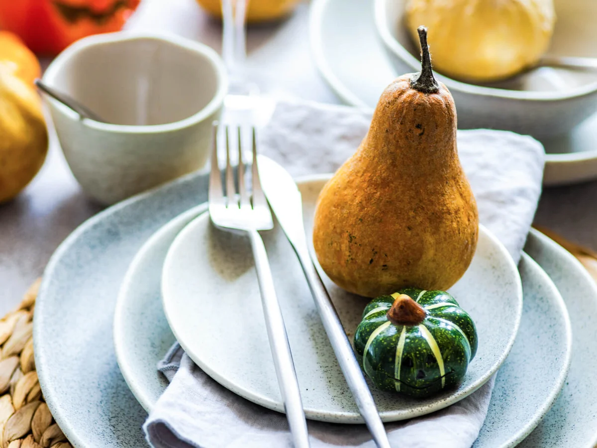 Rustic autumnal Thanksgiving place setting with pumpkins on a table