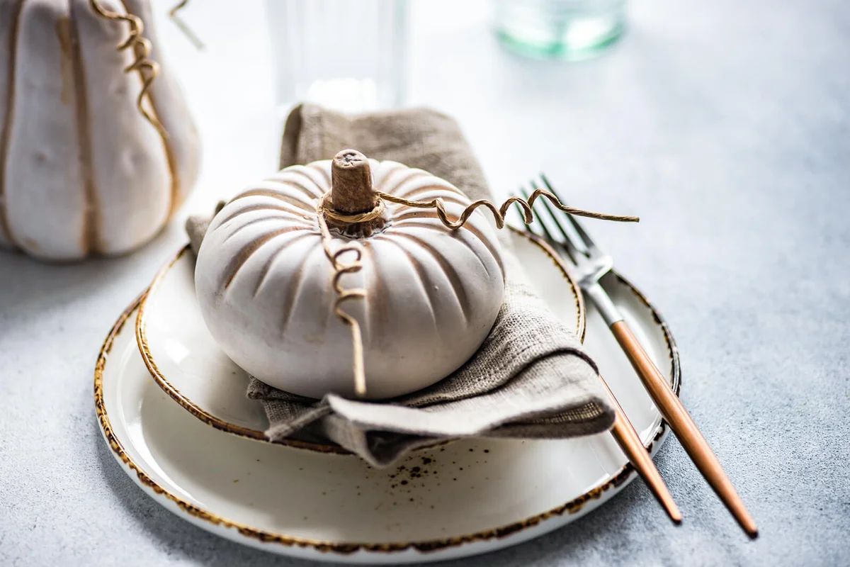 Autumnal Thanksgiving place setting on a table with a pumpkin ornament