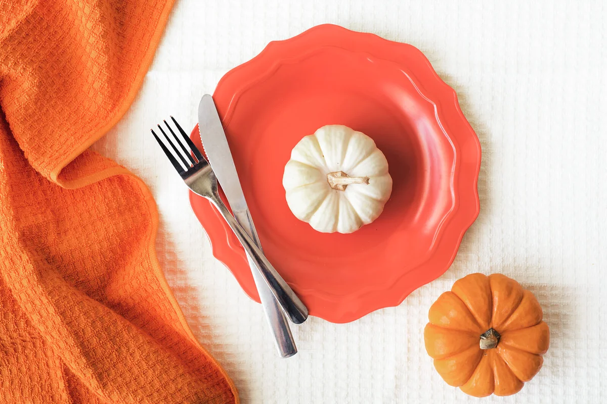 Composition of two mini pumpkins with a plate and silverware on a table