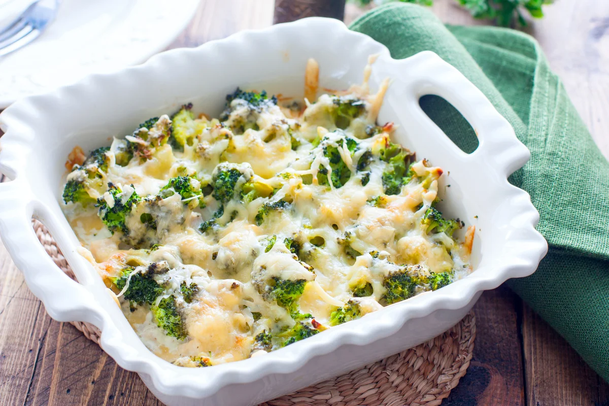 Baked broccoli with chicken in a ceramic form on a wooden table