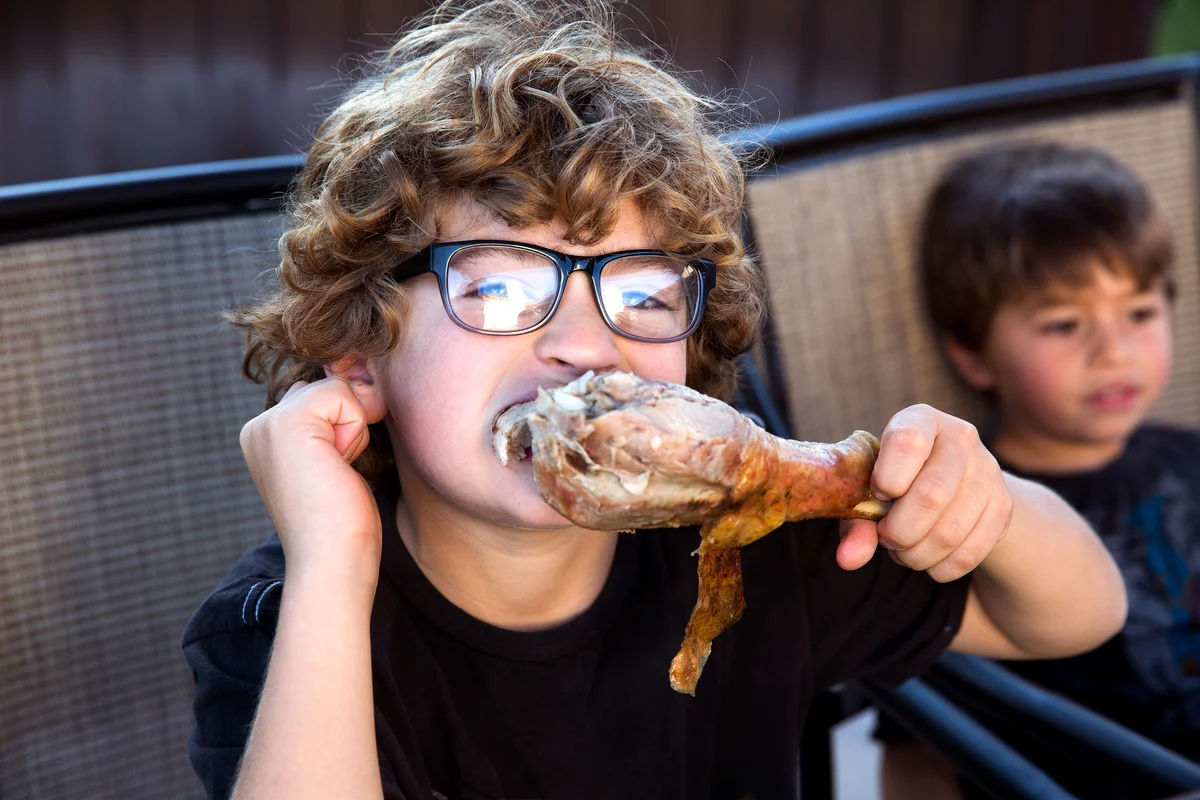 Boy eating turkey leg at Thanksgiving