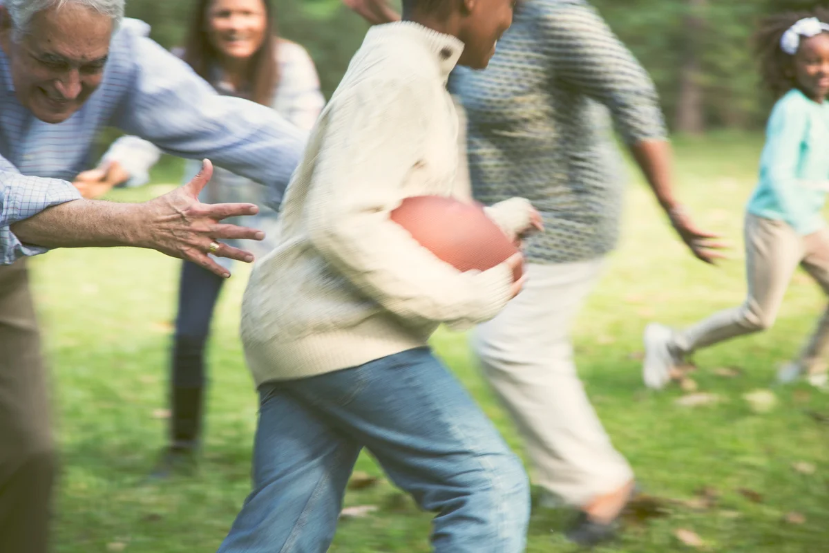 Family playing football in backyard at Thanksgiving