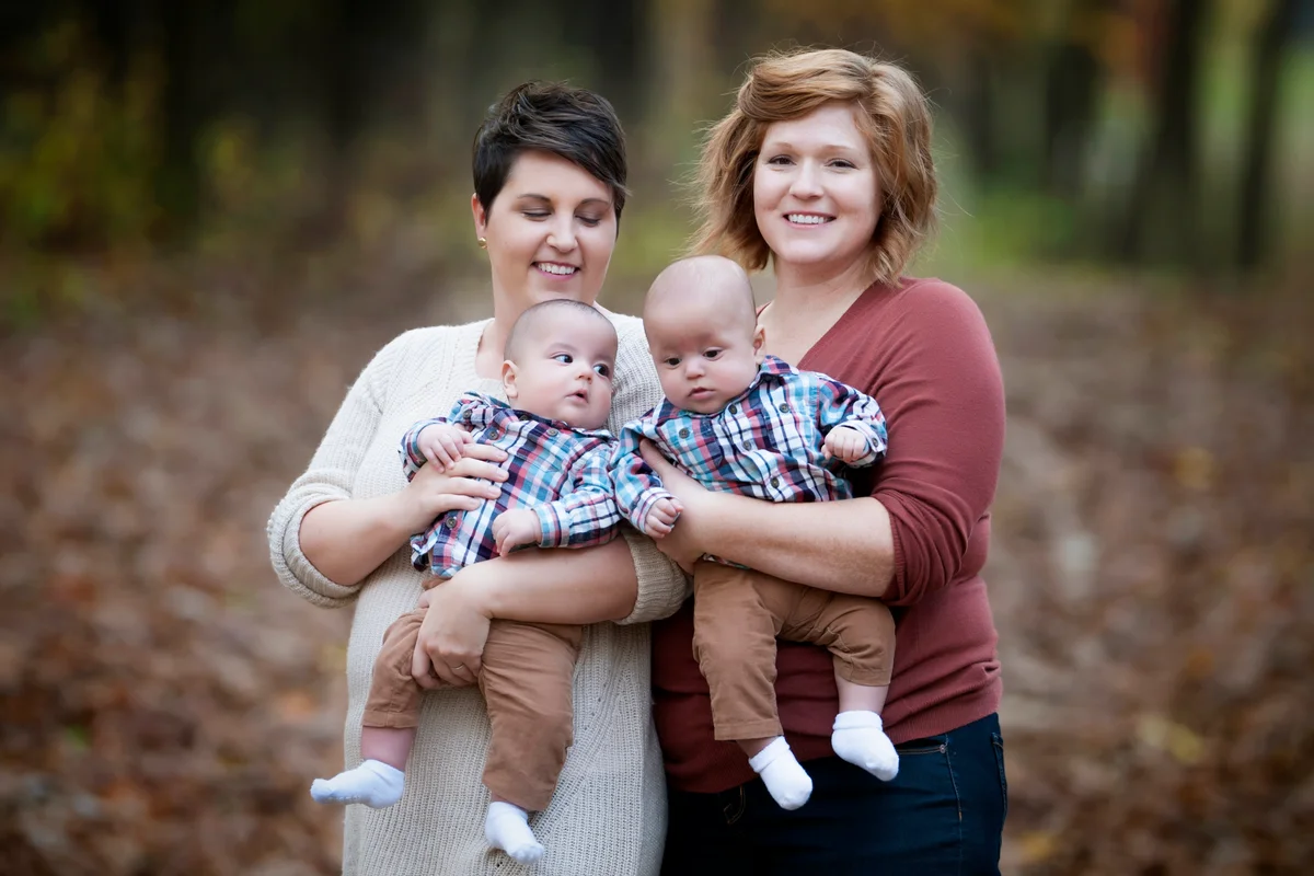 Twins dressed the same hold by their mothers