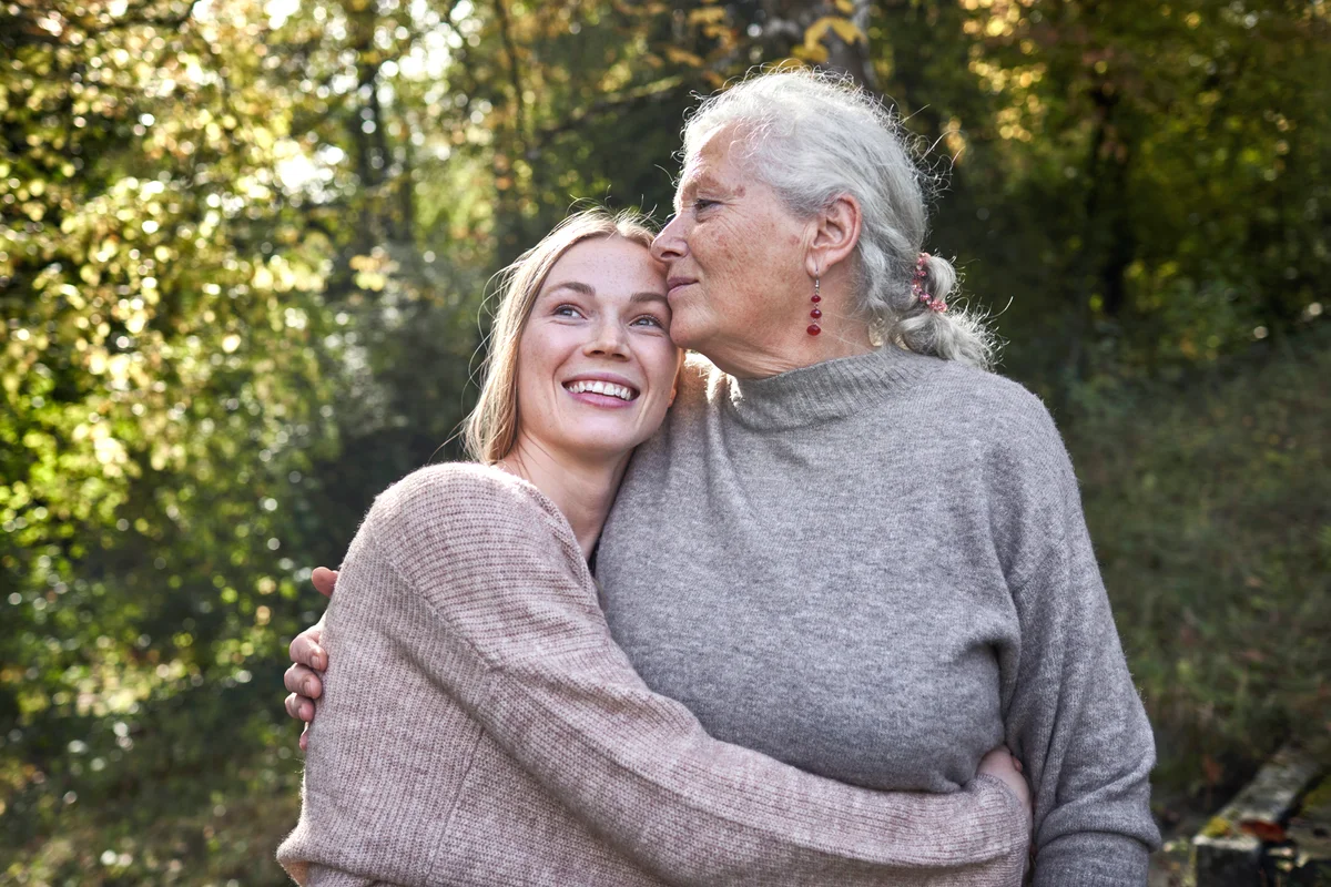 Grandmother and adult granddaughter embracing in garden