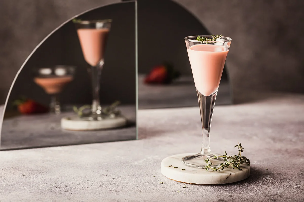 A glass of strawberry liqueur on a gray background