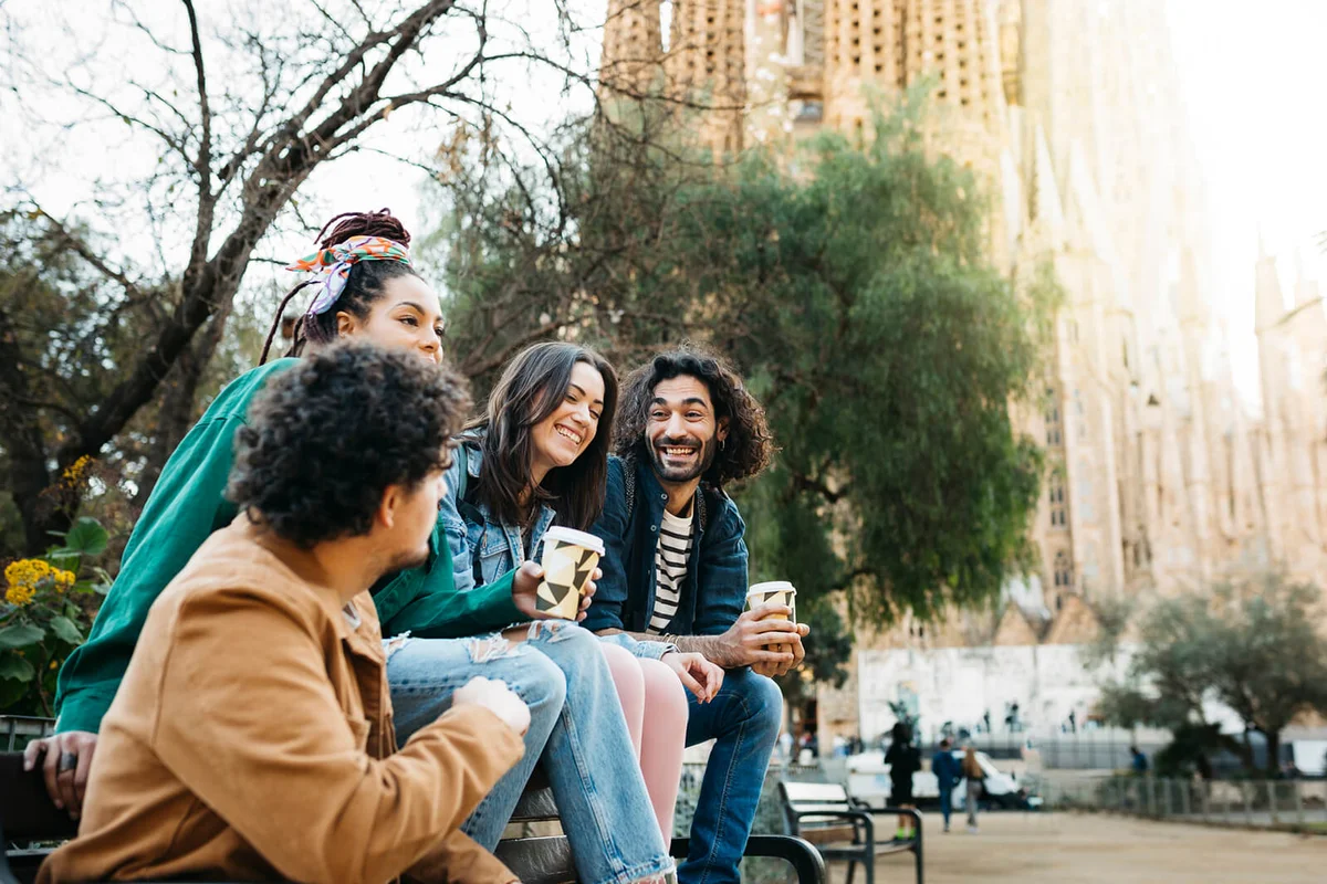 Smiling friends taking selfie while sitting on a bench