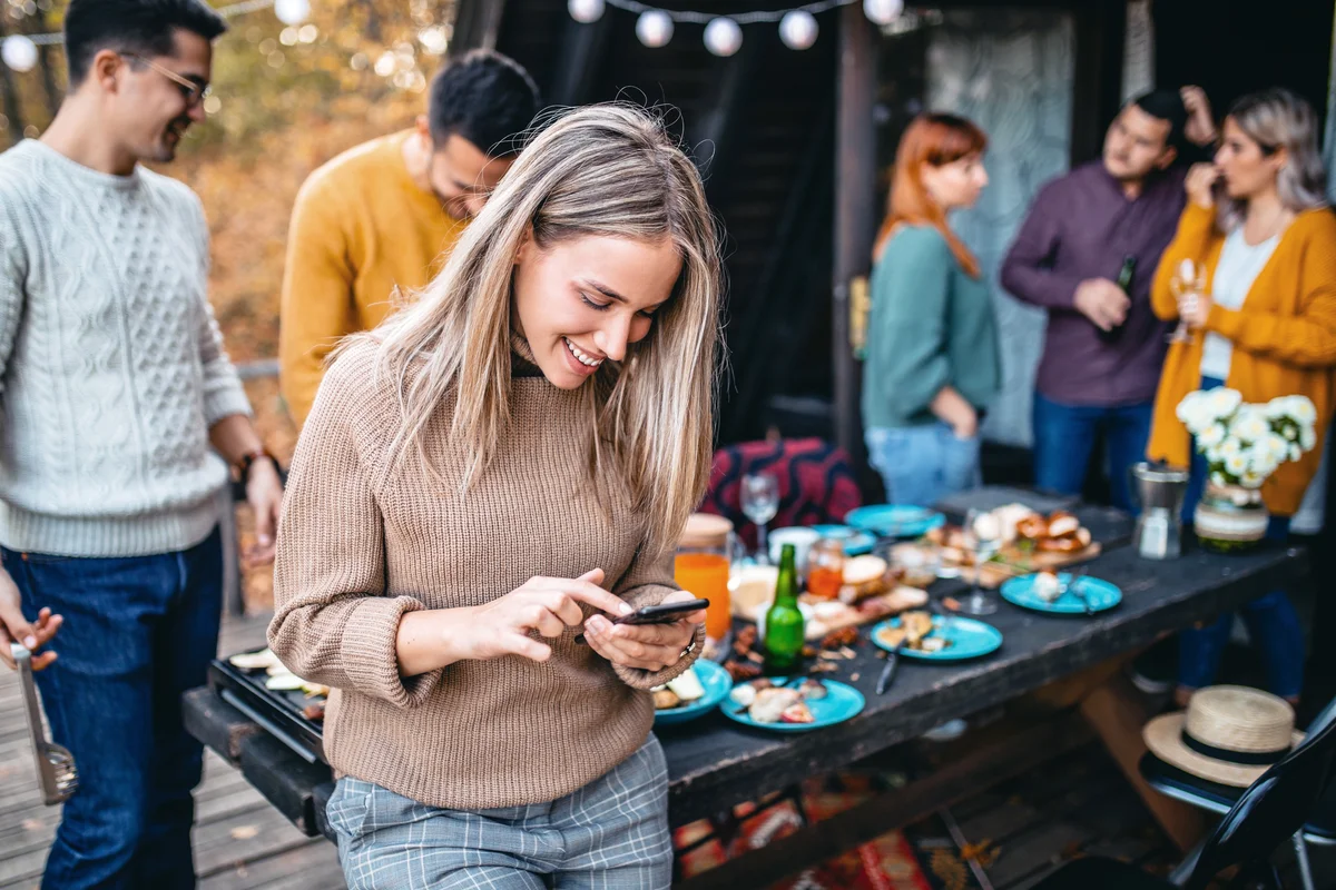 Group of smiling friends enjoys food and conversation at Friendsgiving