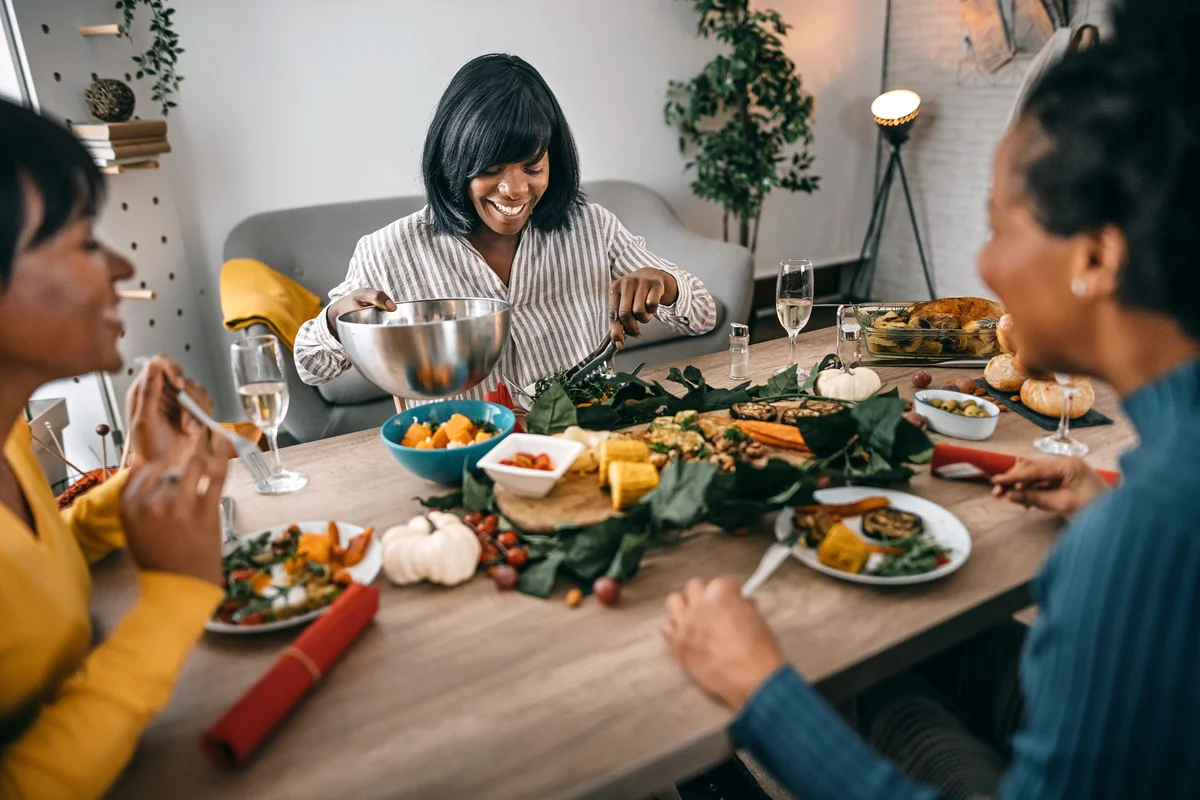 Three friends having food and drinks at home on occasion of thanksgiving