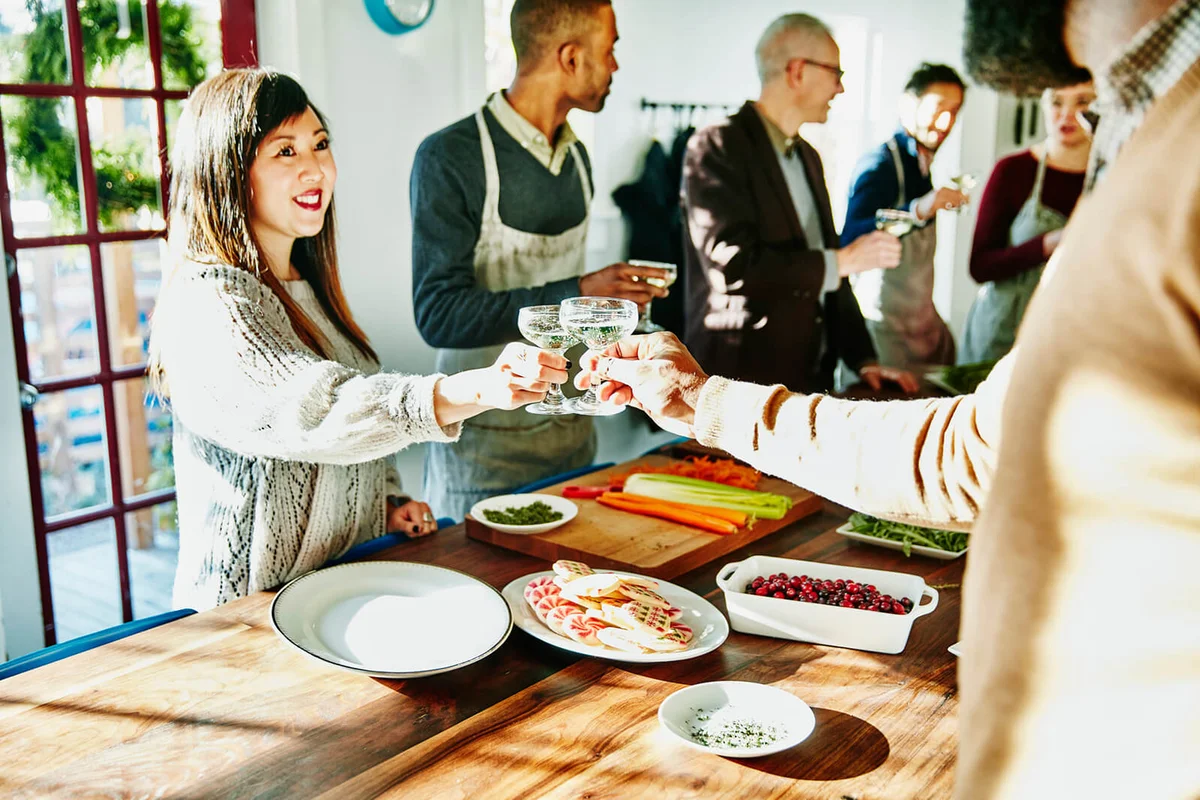Friends toasting with champagne while preparing holiday meal
