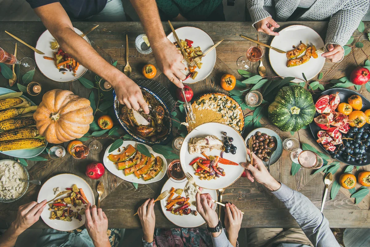 Flat-lay of friends feasting at Thanksgiving Day table with turkey