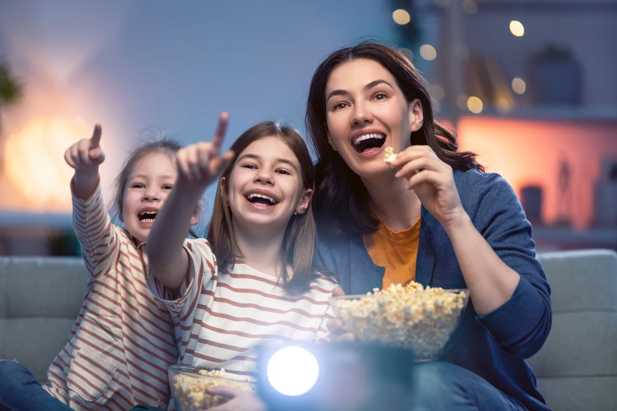 Mother and daughters eating popcorn on 80s movie night