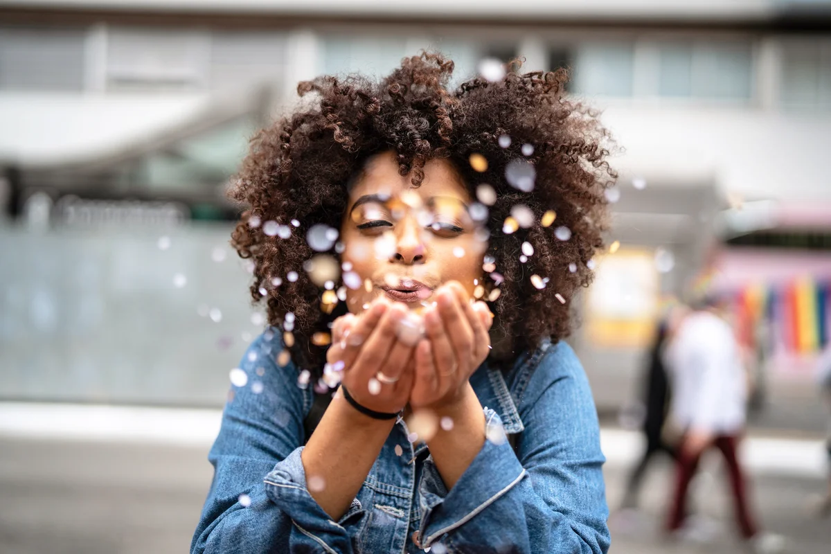 Grateful woman blowing confetti