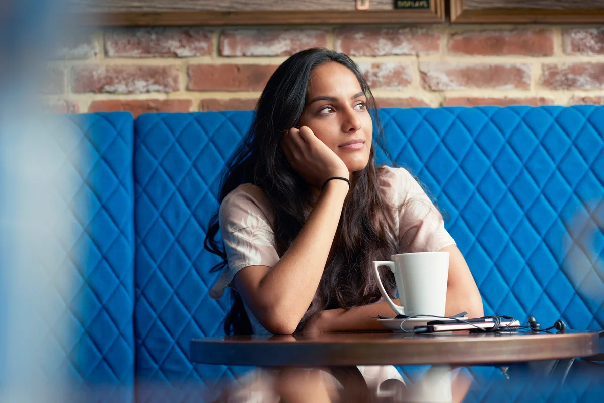 Woman sitting in contemplation at a cafe table