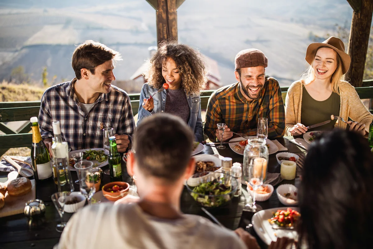 Happy friends talking during lunch on a terrace for thanksgiving
