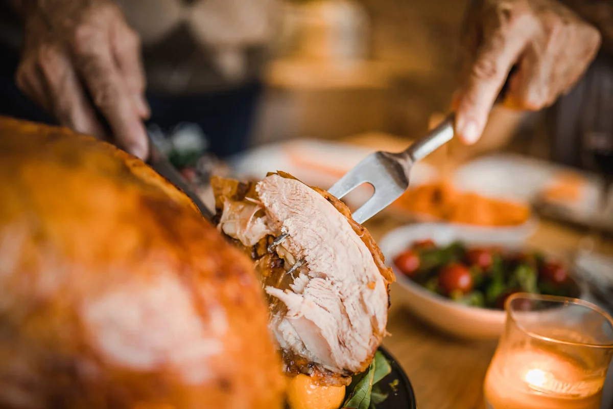 man carving roasted Thanksgiving turkey