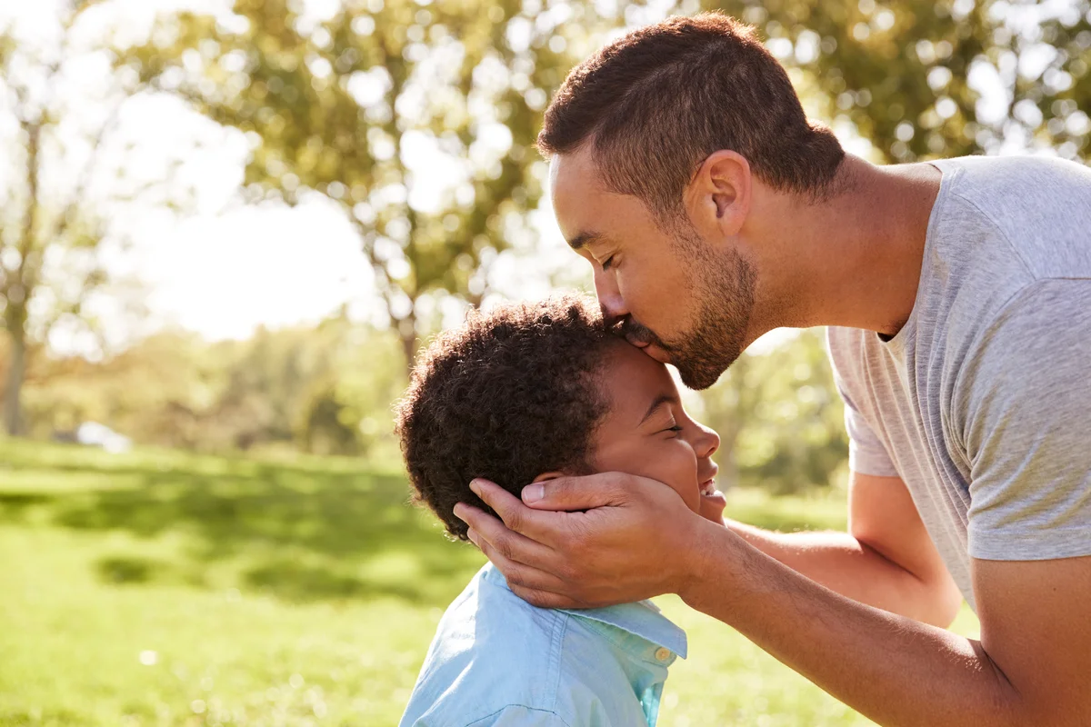 father kissing son's forehead showing support