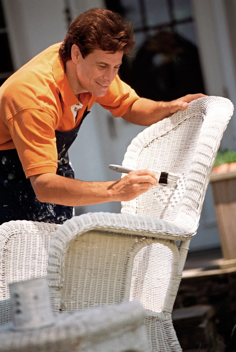 Man painting wicker chair