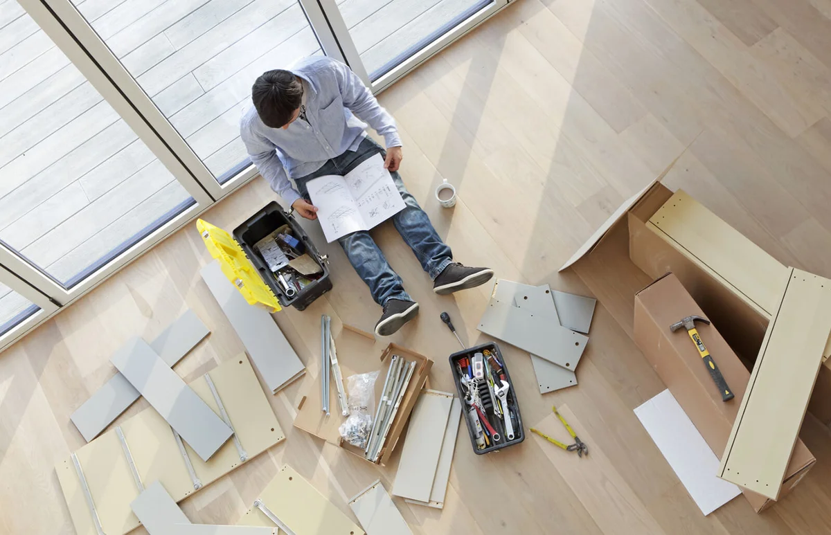 Man sat on floor surrounded by flat pack furniture