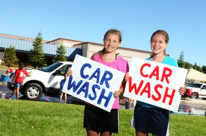 two girls holding car wash signs