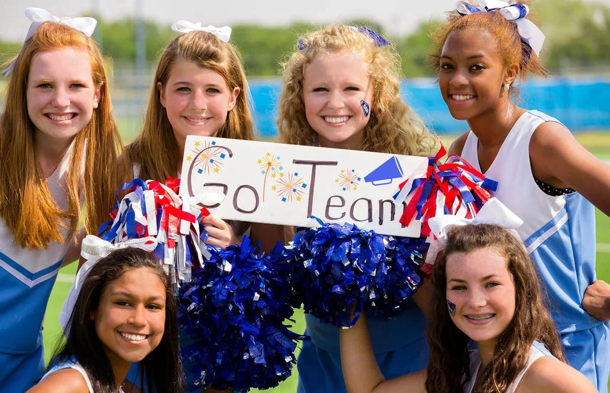 Group of cheerleaders with 'go team' sign