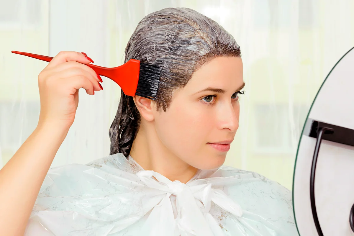 Woman looking in the mirror and dying her hair
