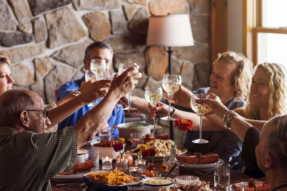 Happy family raising toast while sitting together at dining table during Thanksgiving