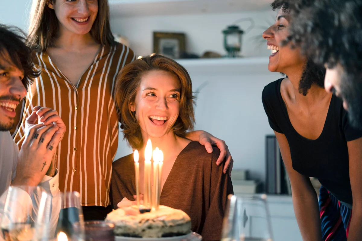 Friends surprising young woman with a birthday cake