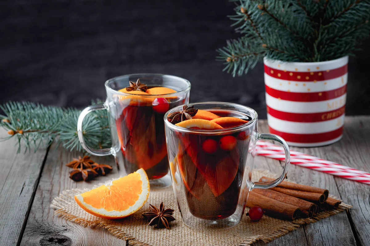 Christmas mulled red wine with spices and oranges on a wooden rustic table