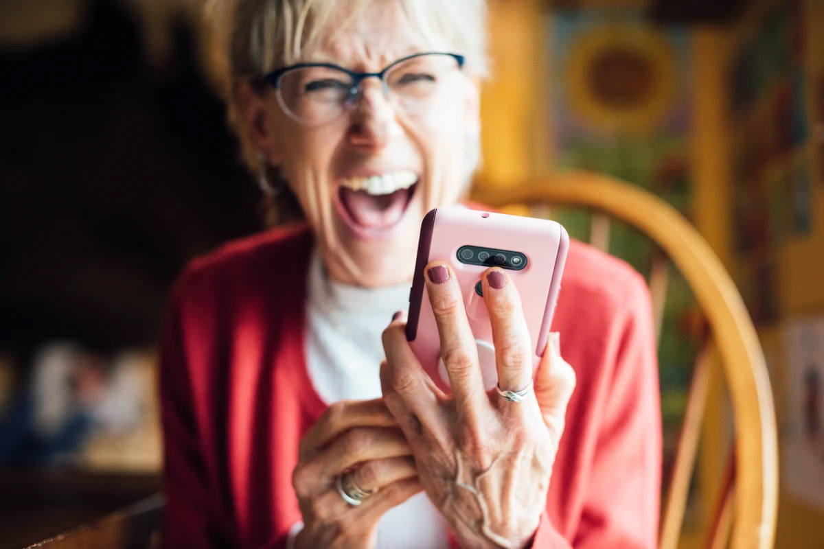 Senior woman laughing while using her smartphone