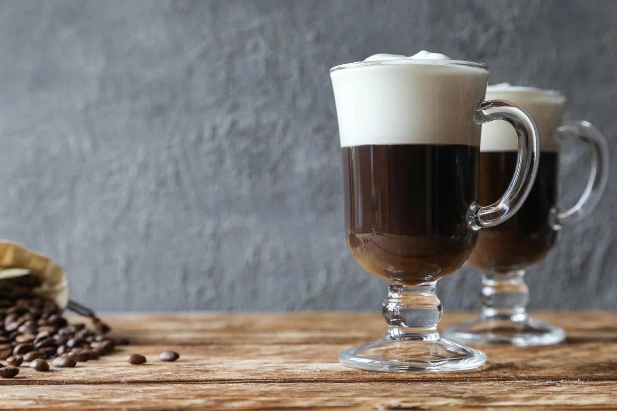 Two Irish coffees with coffee beans on the table
