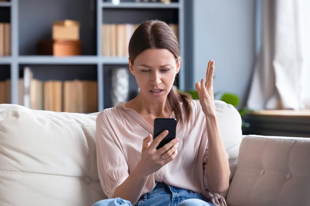 Confused angry young woman having problem with phone