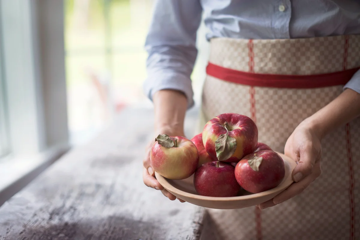Woman holding a bowl of organic red skinned apples
