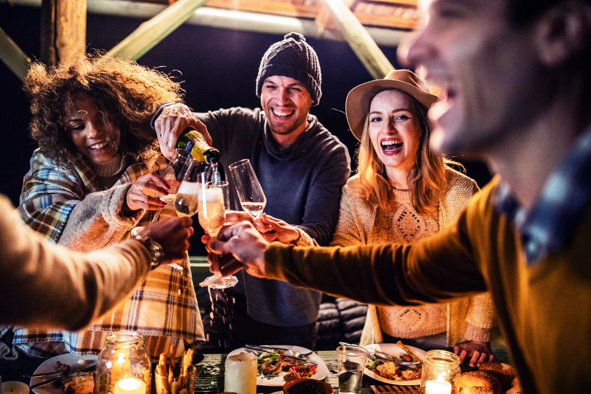 Happy friends drinking champagne on a terrace party during friendsgiving