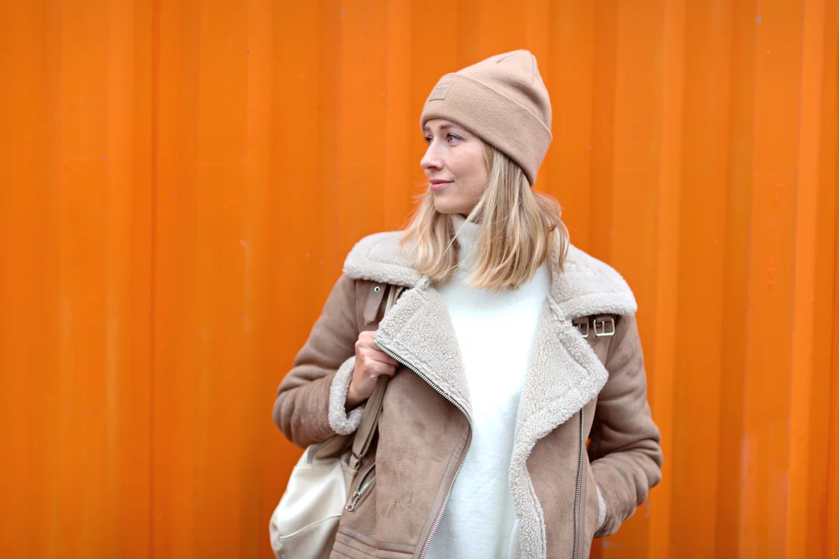 Young woman in casual clothing near orange wall
